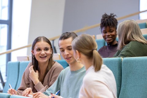 Studierende im Hörsaal, die sich angeregt unterhalten. 
