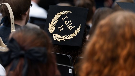 A black hat with the words "I did it" in gold lettering framed by a laurel wreath.
