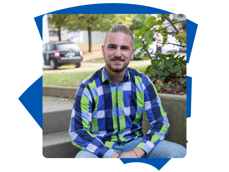 Student Benett der Fakultät Versorgungstechnik sitzt draußen auf der Treppe am Campus Wolfenbüttel und schaut in die Kamera.