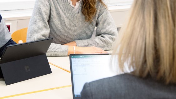 Personen sitzen am Tisch und beraten sich.