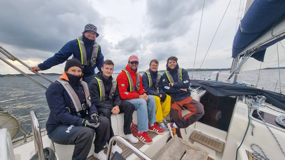 Eine Gruppe Studierender auf einem Segelboot im Meer.