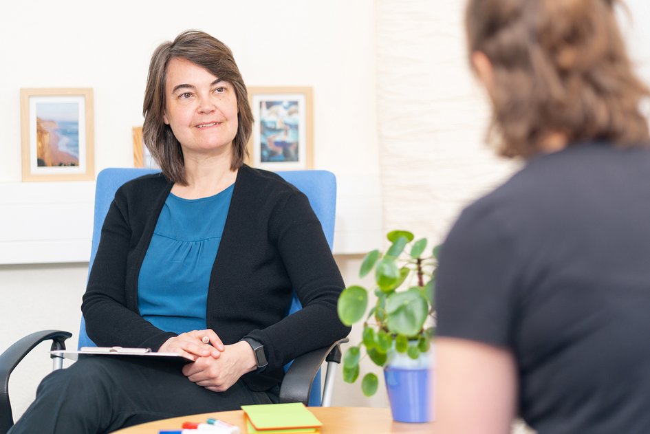 Juliane Quiring sitzt auf einem Stuhl und schaut zu einer Person, die sich gerade von ihr beraten lässt.