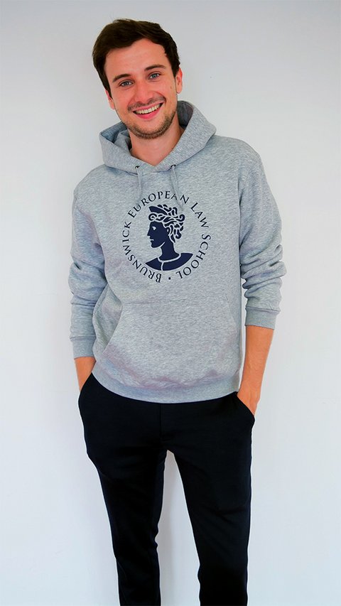 Ein junger Mann trägt den Hoodie der BELS in grau melange. Der Hoodie trägt das Logo der BELS, die Aequitas, über dem Bauch. Darum findet sich der kreisförmig angeordnete Schriftzug "Brunswick European Law School". Das Logo und der Schriftzug sind blau. (öffnet Vergrößerung des Bildes)