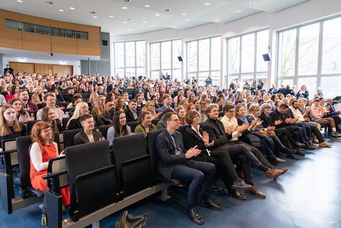 Blick ins Publikum bzw. den Hörsaal in dem die Studierenden zusammen mit ihren Familien und Freunden sitzen. (öffnet Vergrößerung des Bildes)