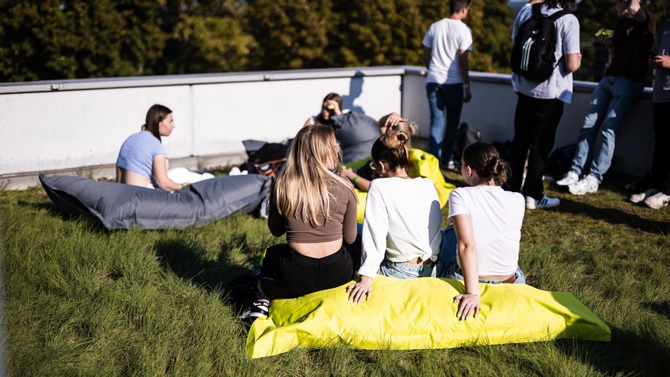Studierendengruppe entspannt auf der Dachterrasse