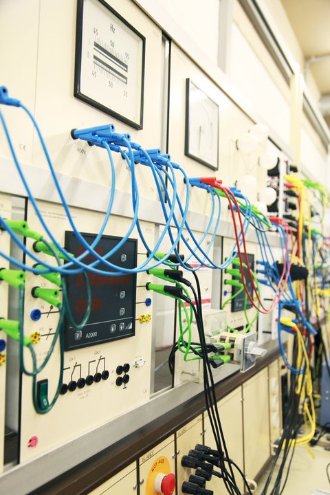 Das Bild zeigt ein im Labor für Elektrotechnik und regenerative Energietechnik aufgebautes Instrumentensteckfeld, das über Sicherheitsmessleitungen mit einem Synchrongenerator verbunden ist, um dessen Verhalten im Insel- und Netzparallelbetrieb zu untersuchen. In der regenerativen Energietechnik werden Synchrongeneratoren beispielsweise in Wasserkraftwerken eingesetzt, wo die mechanische Energie des fließenden Wassers in elektrische Energie umgewandelt wird.