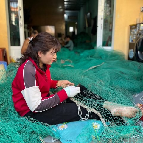 Frau repariert Fischernetze