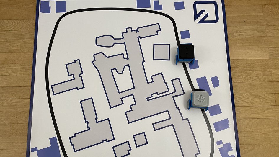 Die Roboter fahren auf einer Leinwand, auf der Gebäude und Straßen nachempfunden sind. 