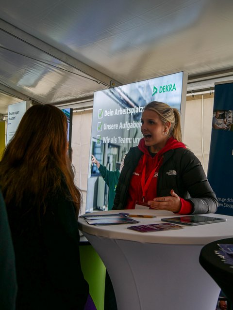 Personen am Info-Stand im Messezelt.