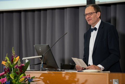 Prof. Dr. Imhof steht am Rednerpult und begrüßt die anwesenden Absolventinnen und Absolventen und weitere Gäste. (öffnet Vergrößerung des Bildes)