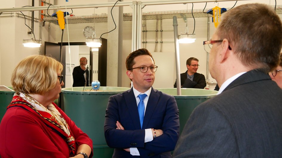 Rosemarie Karger, Falko Mohrs und Klaus Röttcher stehen bei der Eröffnunsgfeier in einer Versuchshalle des INBW