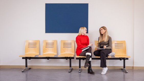 Zwei Studentinnen der Ostfalia sprechen in einem Aufenthaltsbereich der Hochschule miteinander.
