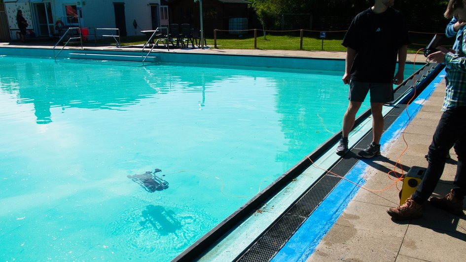 Master's students practise launching an underwater drone in a swimming pool.