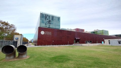 Auf einer Grasfläche steht ein hohes, quadratisches Fundament mit dem Schriftzug der Universidad Politécnica de Valencia. Aus diesem ragen moderne Gebäude mit großen Glasflächen empor. (öffnet Vergrößerung des Bildes)