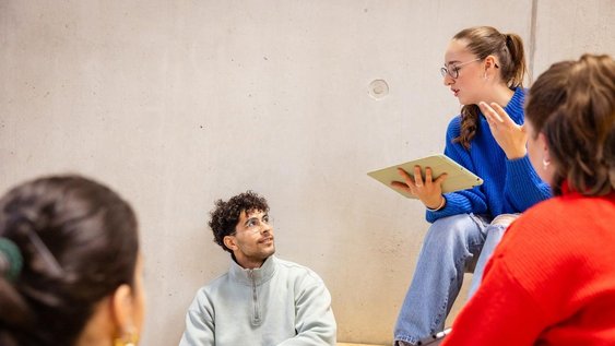 Studierende sitzen auf der Treppe, Studentin mit Tablet in der Hand