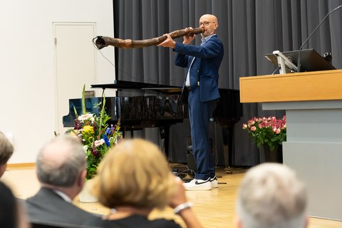 Géza Gál stands on stage and plays the didgeridoo (opens enlarged image)