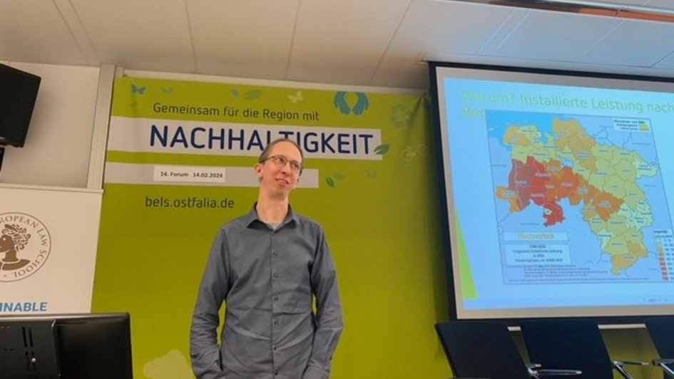 Nanno Peters bei seinem Vortrag. Er steht am Rednerpult und berichtet vom Gründungsprozess der geplanten PV-Genossenschaft "Süd-Ost-Niedersachsen Energiegenossenschaft (SONNE eG i.G.)".