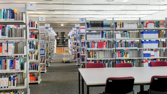 Blick in den Mittelgang des Lesesaals der Bibliothek Wolfsburg mit Buchaufstellung und Arbeitsplätzen