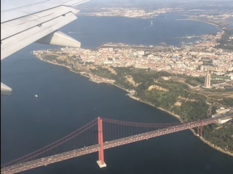 Vogelperspektive aus einem Flugzeug heraus: Zu erkennen ist das Panorama einer Stadt und eine rote Brücke (öffnet Vergrößerung des Bildes)