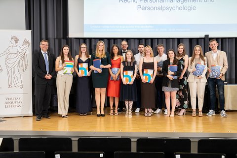 Gruppenbild eines Teils der anwesenden Absolventinnen und Absolventen des Bachelor-Studiengangs Recht, Personalmanagement und Personalpsychologie auf der Bühne. (öffnet Vergrößerung des Bildes)