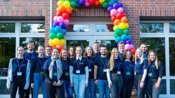 Studenten mit Rucksack lächelt in die Kamera. Sie hat Unterlagen im Arm.