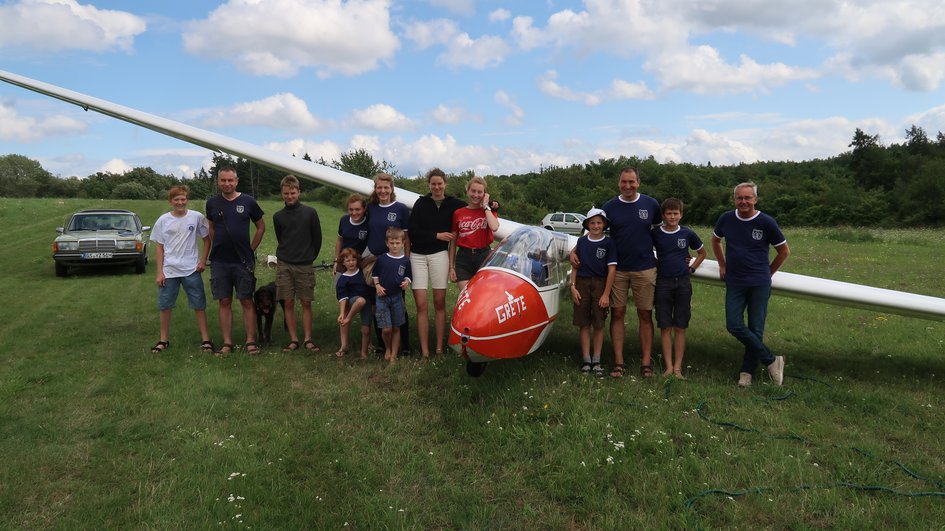 Gruppe mit mehreren Personen, die um einen Segelflugzeug herumstehen