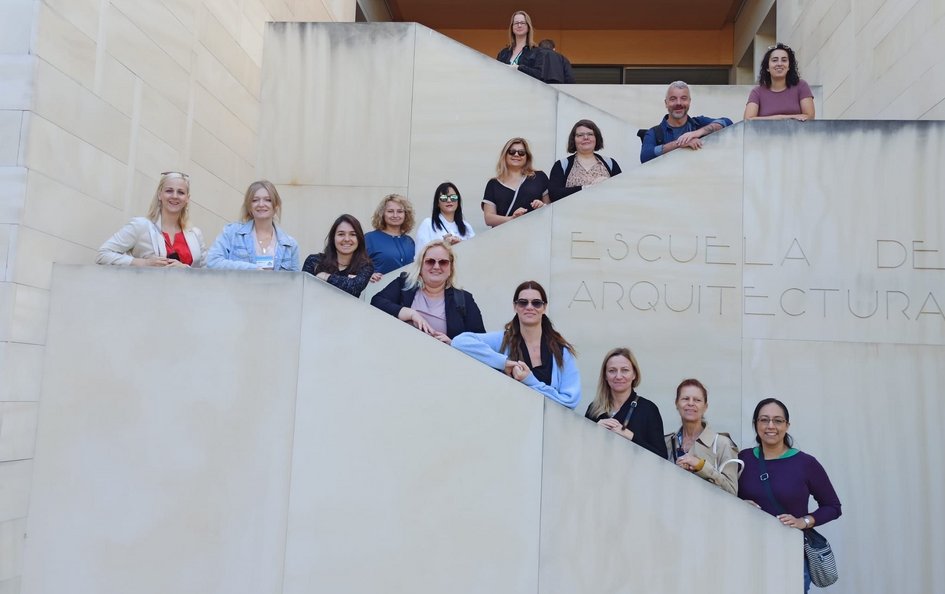 Eine mittelgroße Personengruppe posiert auf einer grauen Betontreppe