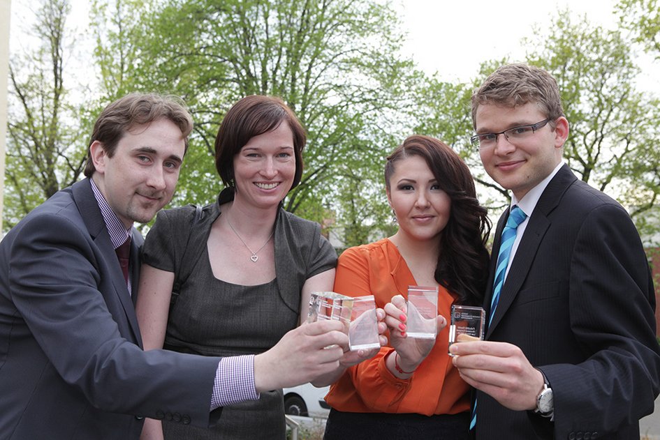 Die Preisträgerinnen und Preisträger präsentieren lächelnd ihre Glasquader, die sie als Auszeichnungen erhalten haben.