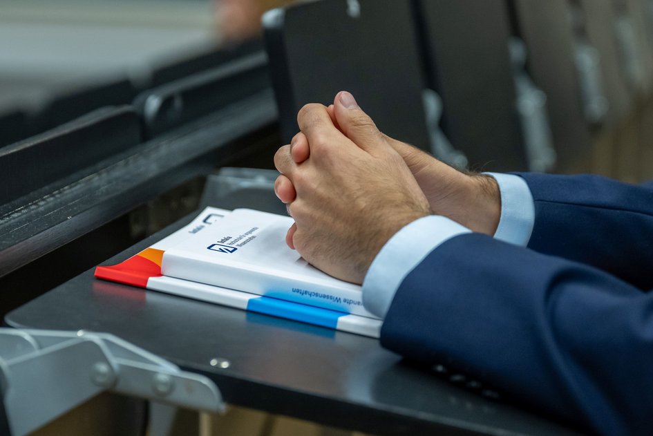 Hände eines Absolventen im Hörsaal bei der Abschlussveranstaltung