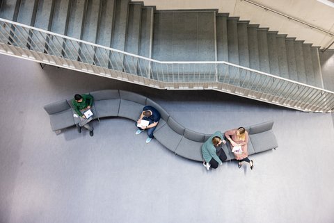 Studierende sitzen auf der Bank im Foyer von Gebäude G