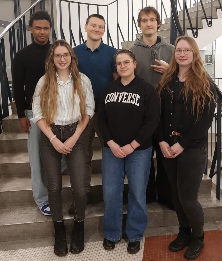 Auf dem Foto sind die Mitglieder des Fachschaftsrats zu sehen. Sechs Studierende stehen auf eine Treppe. In der oberen Reihe drei Studenten, in der unteren Reihe drei Studentinnen.
