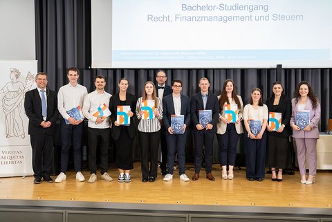 Gruppenbild der anwesenden Absolventinnen und Absolventen des Bachelor-Studiengangs Recht, Finanzmanagement und Steuern auf der Bühne. (öffnet Vergrößerung des Bildes)