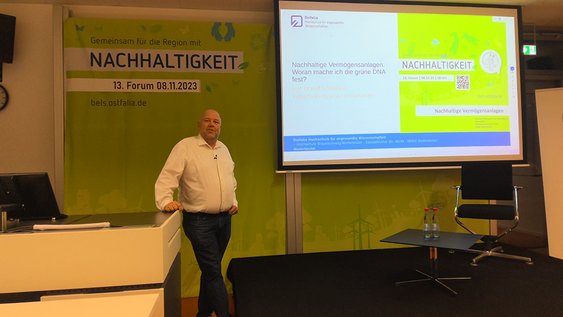 Prof. Dr. Olaf Schlotmann steht am Rednerpult und hält seinen Vortrag zu nachhaltigen Vermögensanlagen.