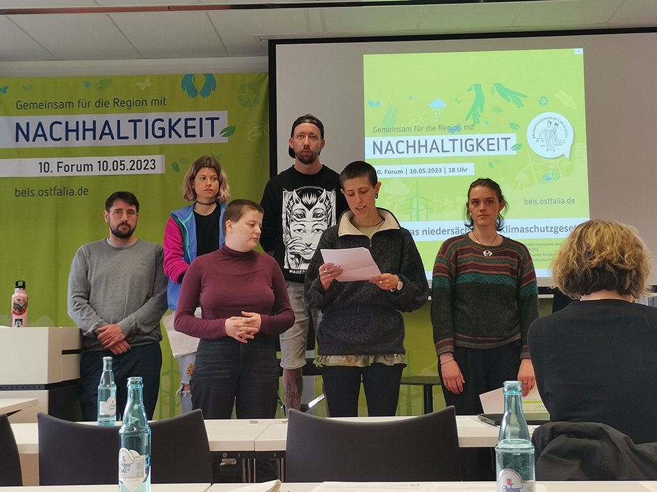 Die Gruppe "Gleichanders" präsentiert beim Forum Nachhaltigkeit ihre Forderungen. Eine Gruppe aus sechs Personen steht vorn, die Forderungen werden verlesen.