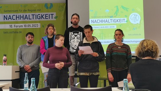 Die Gruppe "Gleichanders" präsentiert beim Forum Nachhaltigkeit ihre Forderungen. Eine Gruppe aus sechs Personen steht vorn, die Forderungen werden verlesen.