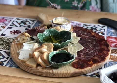 A full wooden plate with various bread spreads and toppings