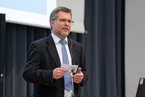 Prof. Dr. Litschen bei der Begrüßung zur Abschlussfeier. Er hält eine Moderationskarte in der Hand. (öffnet Vergrößerung des Bildes)