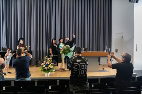 Family members and friends take photos of the graduates on stage. (opens enlarged image)