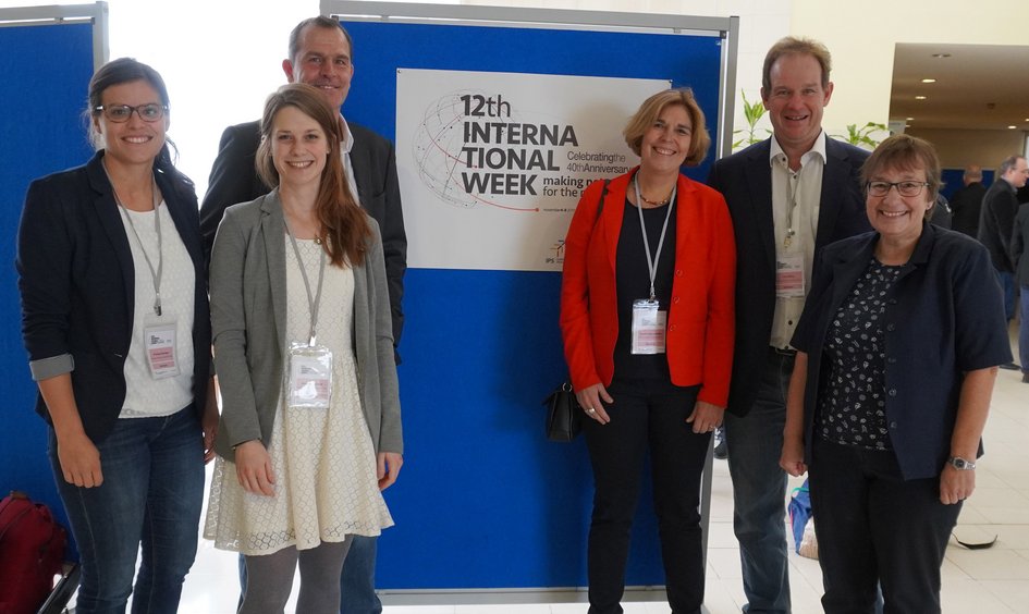 Ostfalia employees stand in front of a billboard during the internal International Week