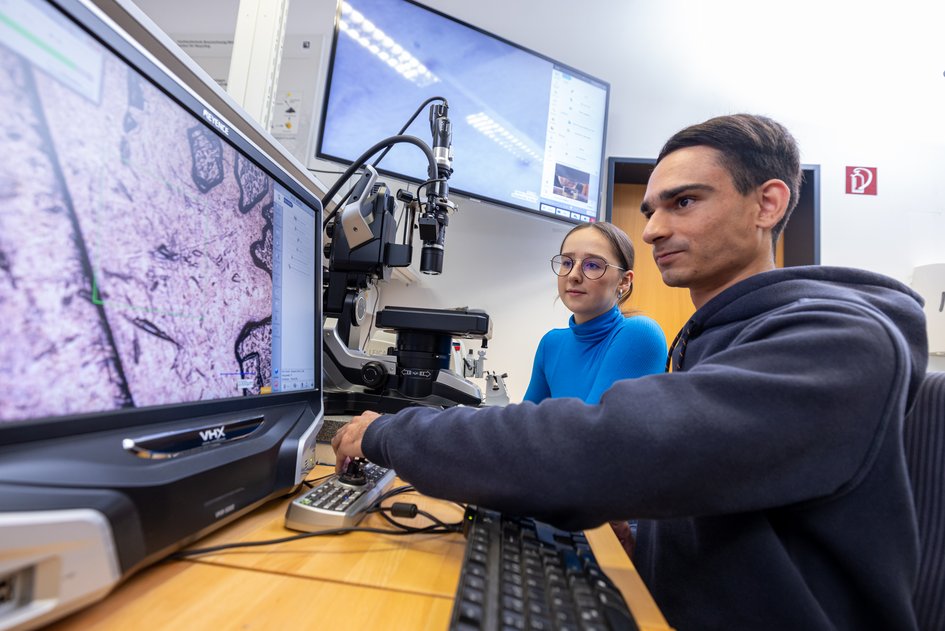Two students working on a microscope