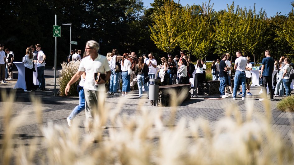 Studierende auf dem Campus, im Vordergrund Pflanzen