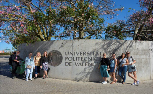 A group of Ostfalia travellers stands in front of a sign reading 'Universidad Politécnica de Valencia'.