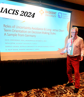 Prof. Launer steht neben einer Präsentation. Der Schriftzug verweist auf die IACIS Conference 2024