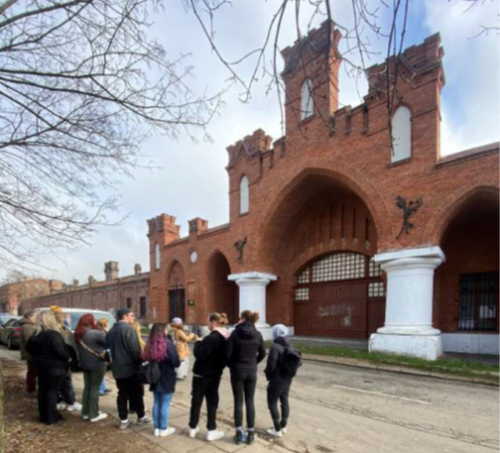 Personen schauen auf eine alte Mauer mit einem großen Torbogen inklusive Tür