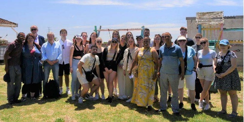Personengruppe posiert auf einer Wiese vor blauem Himmel