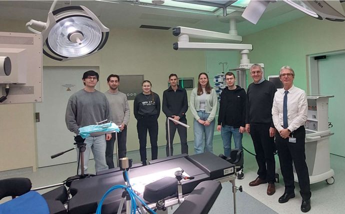 Studierende stehen mit zwei Professoren in einem OP-Saal