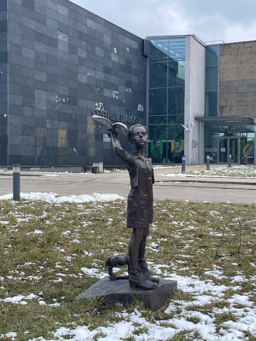 Statue eines Kindes vor den großen, modernen Gebäuden der Gedenkstätte