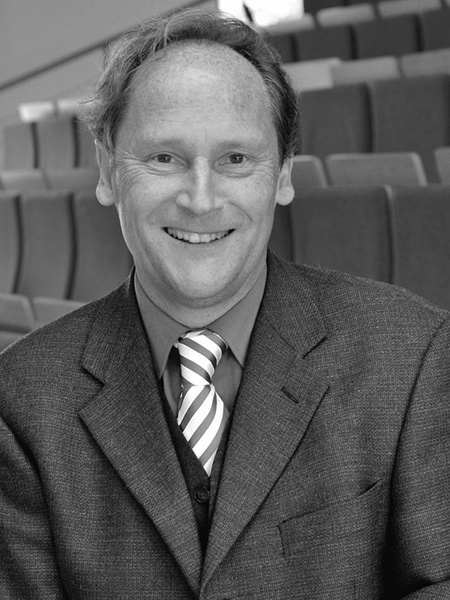 Schwarz-weiß-Bild von Ralph Berens. Er trägt Anzug mit Weste und Krawatte und lächelt in die Kamera.